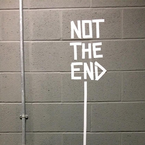 The words It's Not the end in white taped on a grey brick wall